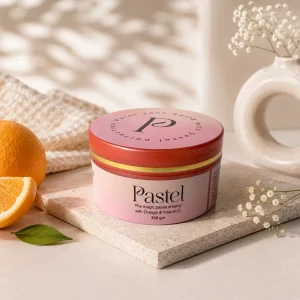 Pastel creamy scrub with Orange and Vitamin C displayed on a modern white platform with soft warm shadows